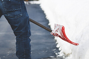 Blade of orange snow shovel hitting into snow bank.