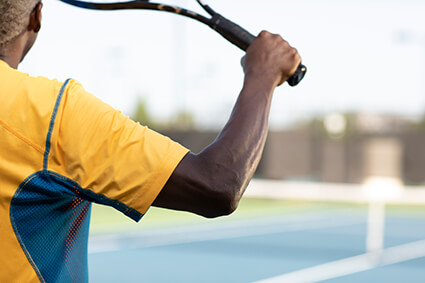 Man on a court holding up a tennis racket.