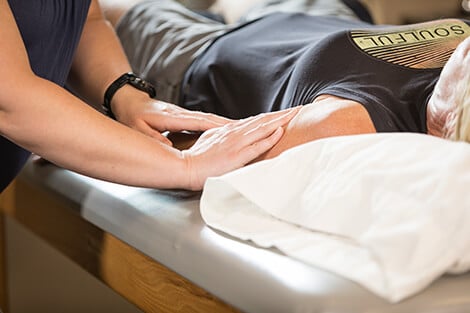 Therapist's hands on a patient's upper arm.